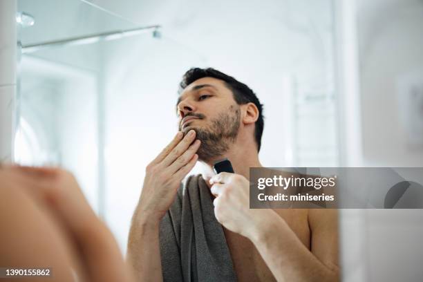 handsome man shaving his beard with an electric razor - electric razor stock pictures, royalty-free photos & images