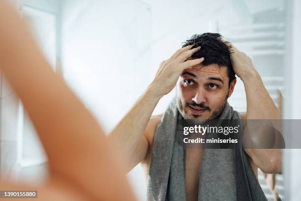 handsome man styling his hair in a bathroom - examining hair stock pictures, royalty-free photos & images