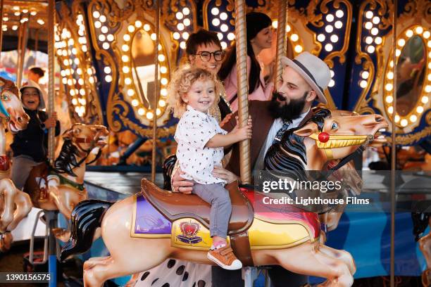 parents ride carousel with toddler son - children funny moments stock pictures, royalty-free photos & images