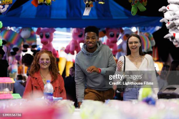 three smiling friends play carnival game - awards night stock-fotos und bilder