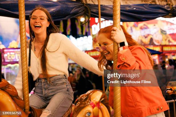 best friends ride a carousel together - traveling carnival stockfoto's en -beelden