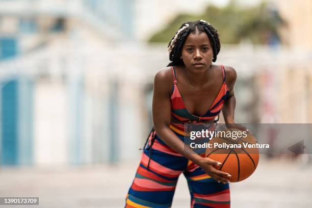 young woman holding a basketball in the street - streetball stock pictures, royalty-free photos & images