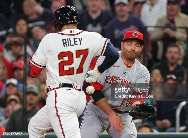 Austin Riley of the Atlanta Braves is hit by the ball on a throwing error by Brandon Drury of the Cincinnati Reds as he crosses first base in front...