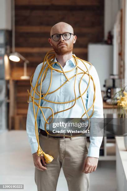 young businessman covered with cable standing in office - inesperado fotografías e imágenes de stock