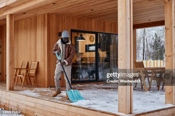 man shoveling snow from porch outside house in winter - building elements stock pictures, royalty-free photos & images