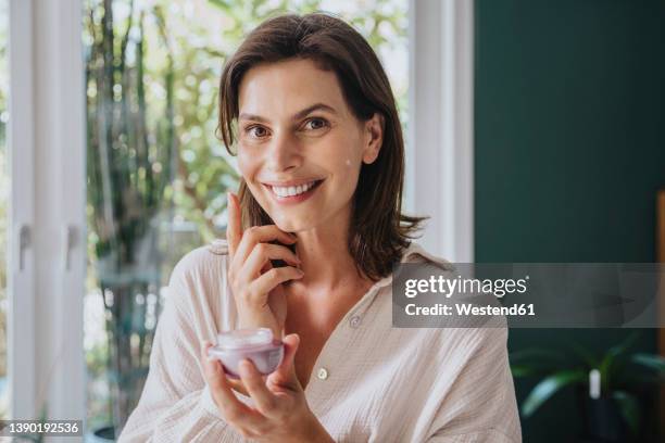 smiling woman doing skin care at home - woman portrait skin stock-fotos und bilder
