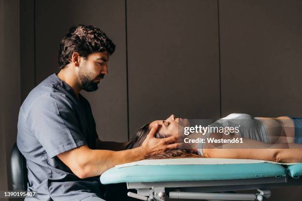 physiotherapist giving head massage to woman in medical clinic - head massage stock pictures, royalty-free photos & images