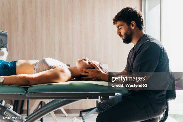 physiotherapist doing head massage to woman at medical clinic - physiotherapist stock-fotos und bilder