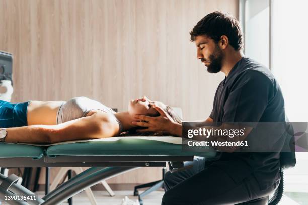 physiotherapist doing head massage to woman at medical clinic - head massage fotografías e imágenes de stock