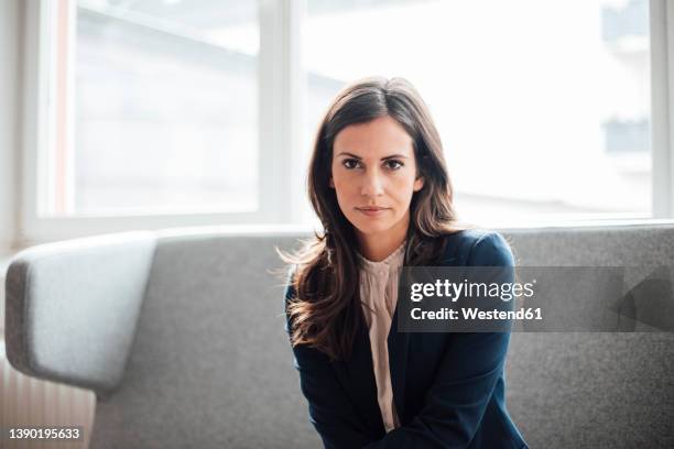 businesswoman sitting on sofa at office - businesswoman couch fotografías e imágenes de stock