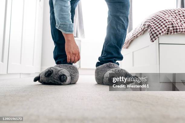 man wearing wolf paw slippers in bedroom at home - pantoffel stockfoto's en -beelden