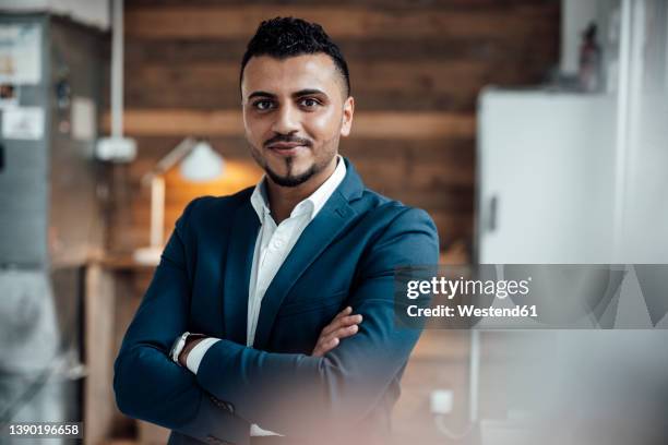 businessman standing with arms crossed at work place - nordafrikanischer abstammung stock-fotos und bilder