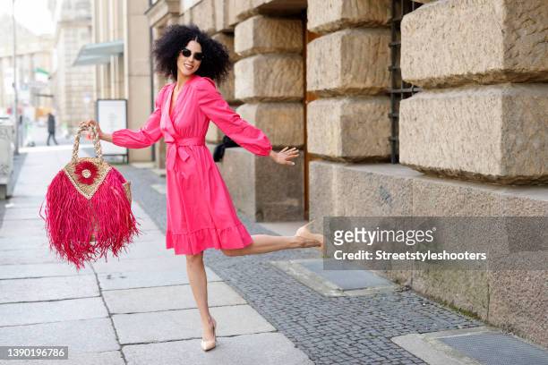 Model and artist Zoe Helali wearing a pink midi dress by Miss Goodlife, a beige and pink bast bag with fringe detail by Miss Goodlife, sunglasses by...