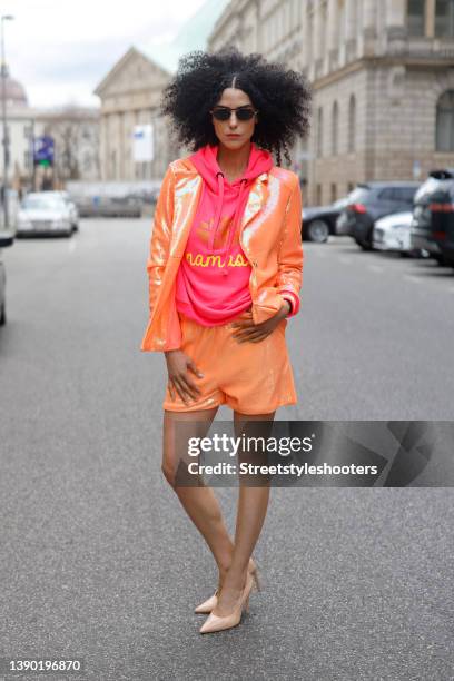 Model and artist Zoe Helali wearing an orange sequin blazer and matching shorts by Miss Goodlife, a pink hoodie by Miss Goodlife, sunglasses by...