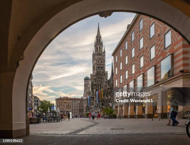 germany, bavaria, munich, view of marienplatz with arch in foreground and new town hall in background - new town hall munich stockfoto's en -beelden