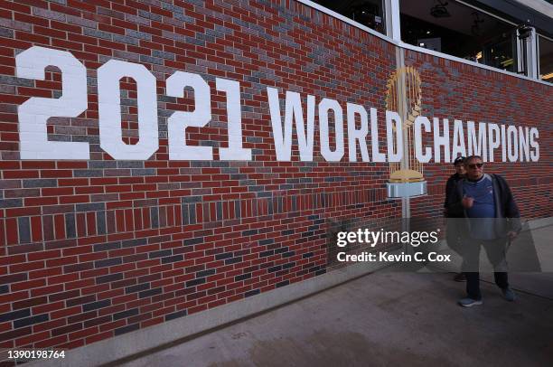 Fans walk past a 2021 World Champions logo in the upper deck prior to the opening day game between the Atlanta Braves and the Cincinnati Reds at...