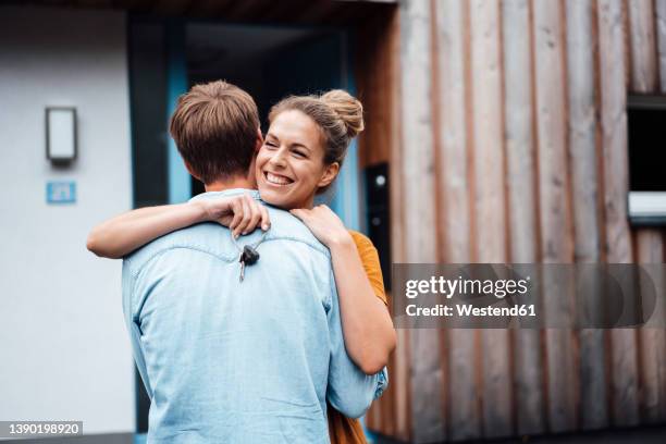 happy woman with house key hugging boyfriend - hausschlüssel stock-fotos und bilder