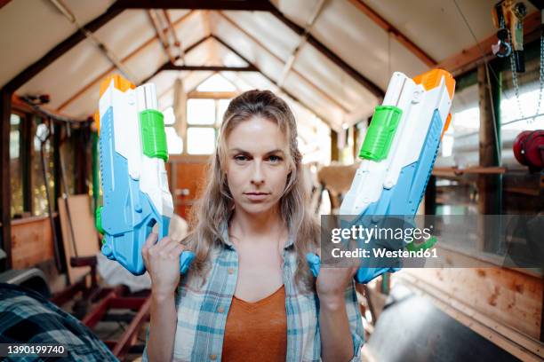 blond woman with toy guns in garage - toy gun stock pictures, royalty-free photos & images