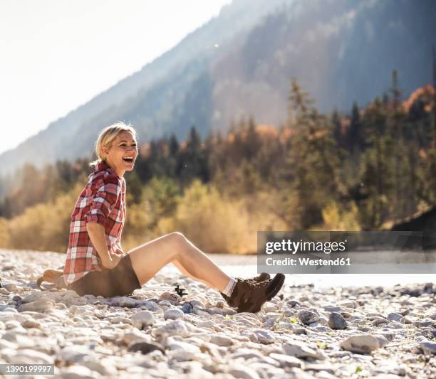 austria, alps, laughing woman on a hiking trip having a break at a brook - skogshuggarskjorta bildbanksfoton och bilder