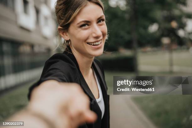 happy young woman holding boyfriend's hand on footpath - young couple holding hands stock pictures, royalty-free photos & images