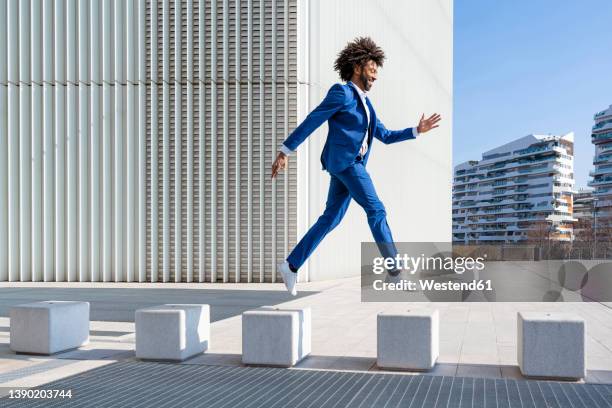 playful businessman jumping on concrete block - jumping stock pictures, royalty-free photos & images