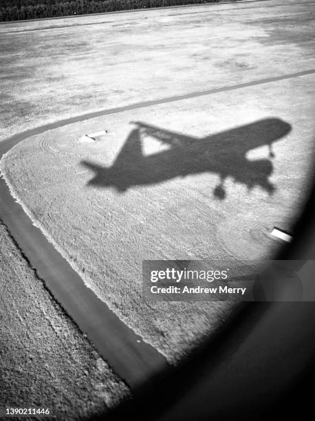 airplane shadow landing at airport, passenger window view, black and white - straßenmarkierung stock-fotos und bilder