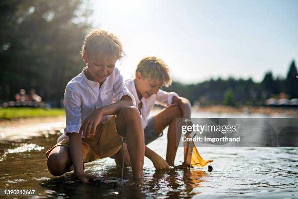 little boys are playing with little toy boats in the lake. - ankle deep in water bildbanksfoton och bilder