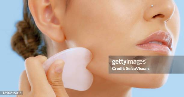 studio shot of a beautiful young woman using a gua sha tool on her face - spooning stock pictures, royalty-free photos & images