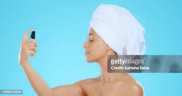 studio shot of a young woman spraying a product on her face - perfume sprayer bildbanksfoton och bilder