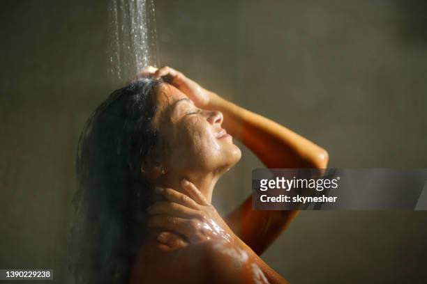 woman enjoying while washing hair with her eyes closed. - dusch bildbanksfoton och bilder