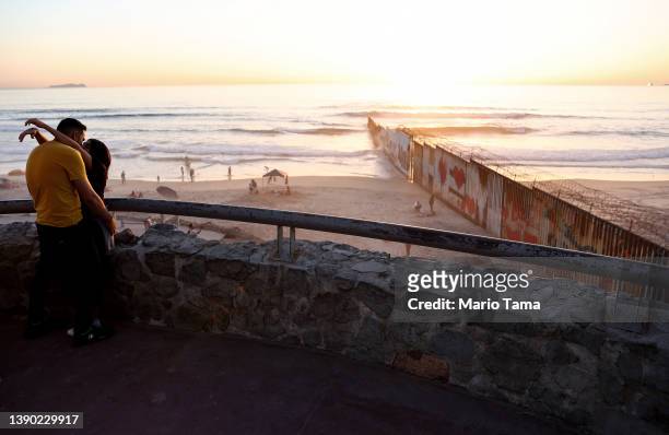 People embrace near the U.S.-Mexico border barrier which extends into the Pacific Ocean on April 7, 2022 in Tijuana, Mexico. March 21st marked the...