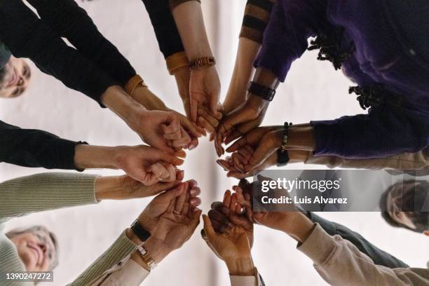 people with fist put together during support group session - kooperation stock-fotos und bilder