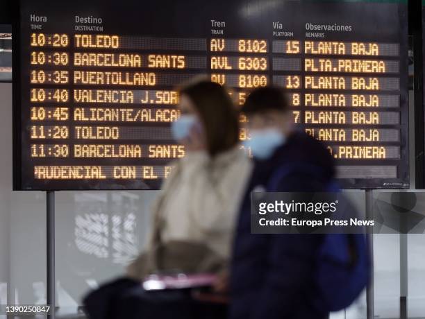 People, with suitcases, pass by a panel of departures with different destinations, on the day the Easter Week 2022 departure operation starts, at...