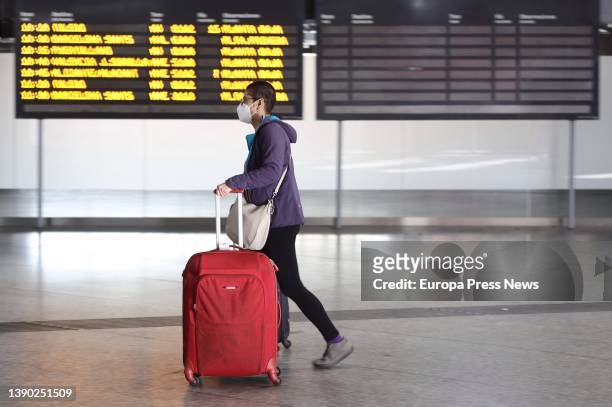 Boy, carrying suitcases, walks past a panel of departures with different destinations, on the day the Easter Week 2022 departure operation starts, at...