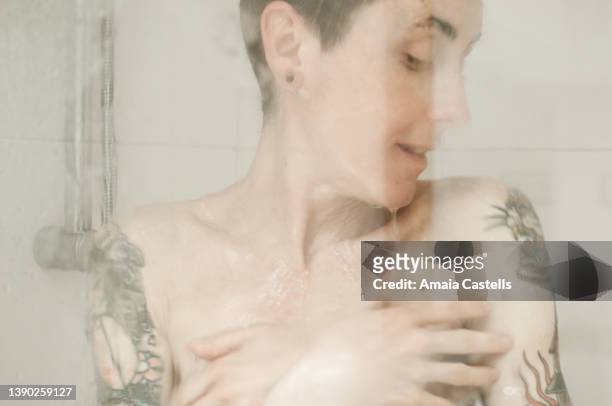mujer tatuada dándose una ducha. - ducha stock-fotos und bilder