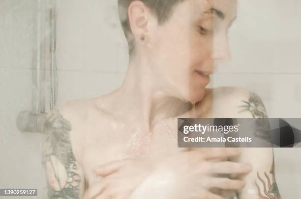 mujer tatuada dándose una ducha. - woman in shower tattoo stock pictures, royalty-free photos & images