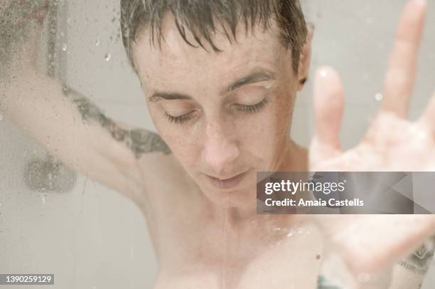 mujer en la ducha con manos apoyadas en la mampara. - ducha stock pictures, royalty-free photos & images