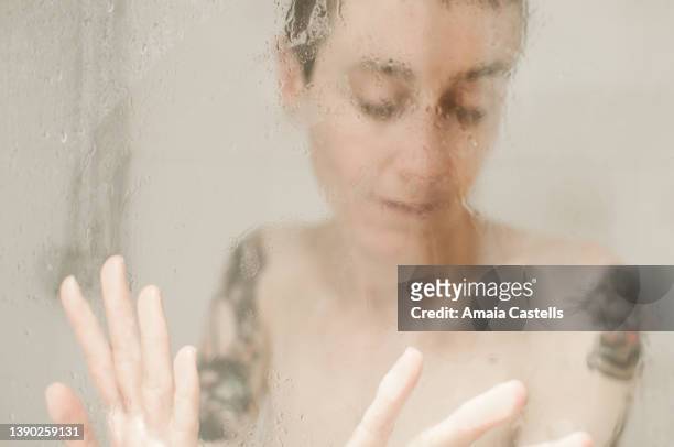mujer tatuada desenfocada tras mampara de ducha. - ducha stock pictures, royalty-free photos & images
