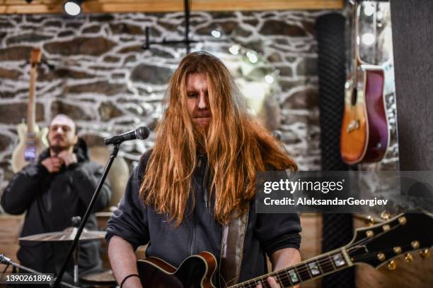 guitarrista calentando mientras el baterista se prepara para grabar en estudio - heavy fotografías e imágenes de stock