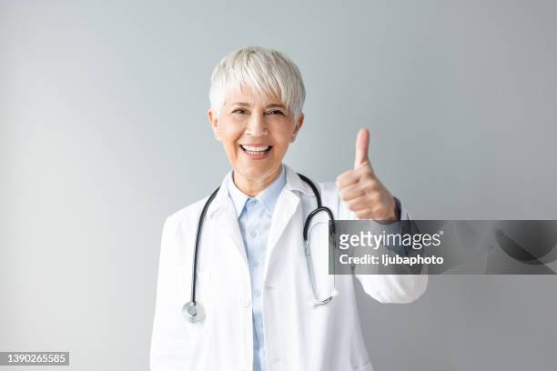 portrait of an attractive mature female doctor giving thumbs up - giving feedback stock pictures, royalty-free photos & images