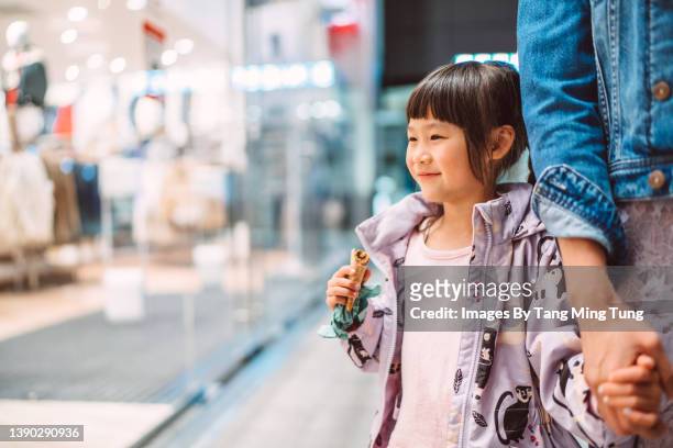 lovely little girl having window shopping with her mom joyfully in shopping mall - chinese young adults shopping imagens e fotografias de stock