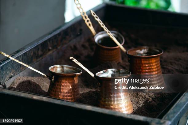 the process of making coffee in a turkish cezve on the sand, in a street cafe, outdoors. metal turk, close-up. the concept of breakfast, coffee break, tourism and travel. - arabica coffee drink stock pictures, royalty-free photos & images