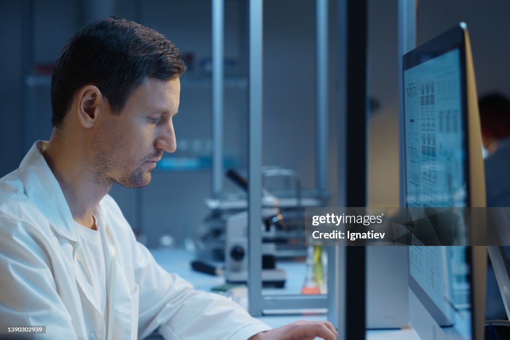 A scientist working late on his computer in a modern laboratory