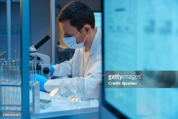 ein molekularbiologe, der mit einem mikroskop in einem modernen wissenschaftlichen labor arbeitet - genome sequencing stock-fotos und bilder