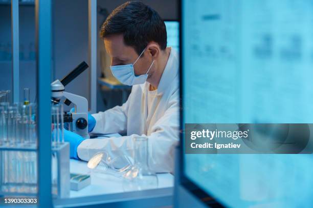 ein molekularbiologe, der mit einem mikroskop in einem modernen wissenschaftlichen labor arbeitet - bioinformatik stock-fotos und bilder