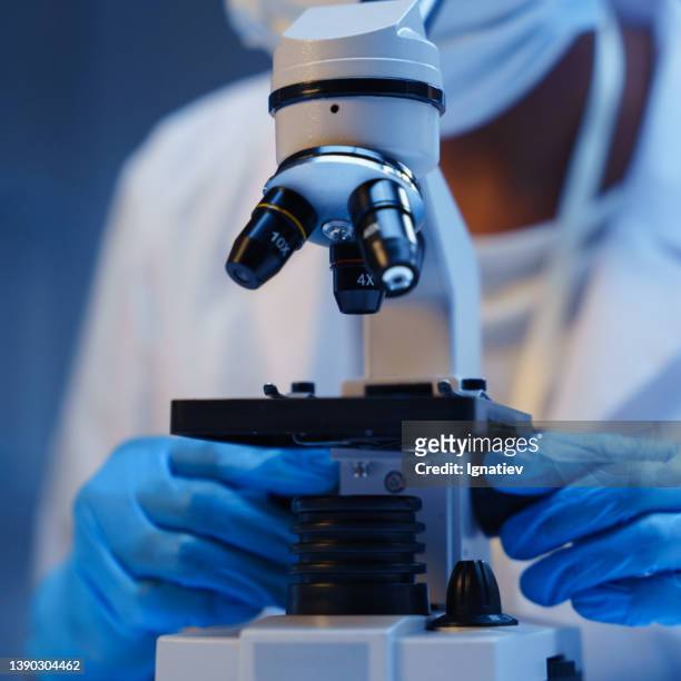 nahaufnahme eines mikroskops und der hände eines wissenschaftlers in schutzhandschuhen - genome sequencing stock-fotos und bilder