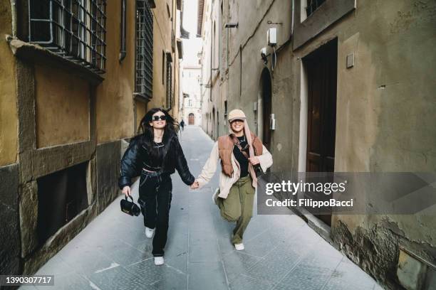 two friends are running together in an ancient alley - alley stock pictures, royalty-free photos & images