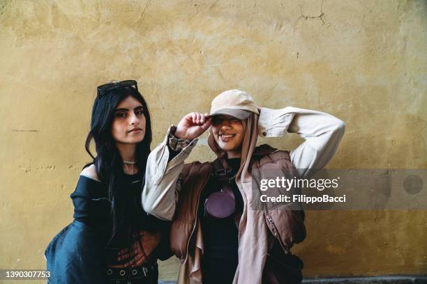 portrait of two young adult funky girls against a yellow wall - all hip hop models stock pictures, royalty-free photos & images