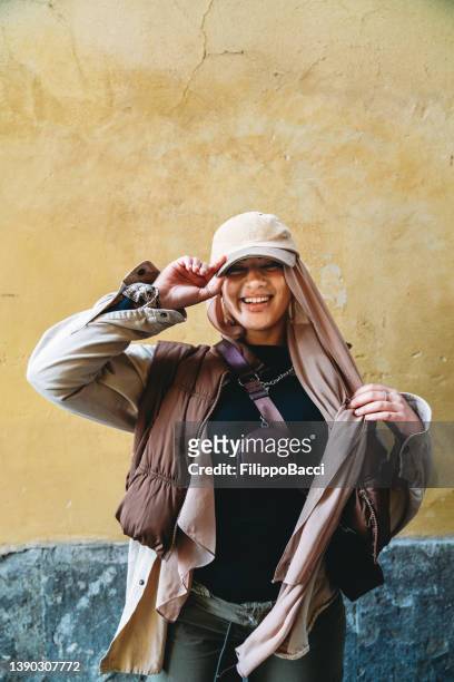 portrait of a young adult woman against a yellow background - hijab fashion stockfoto's en -beelden