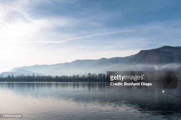 italy, mountains and trees reflected in calm lake - 巻雲 ストックフォトと画像